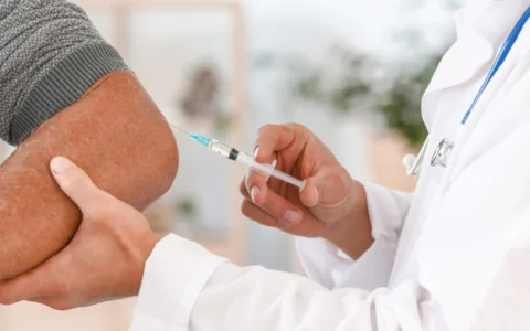 Doctor administering BPC-157 injection into man's elbow.